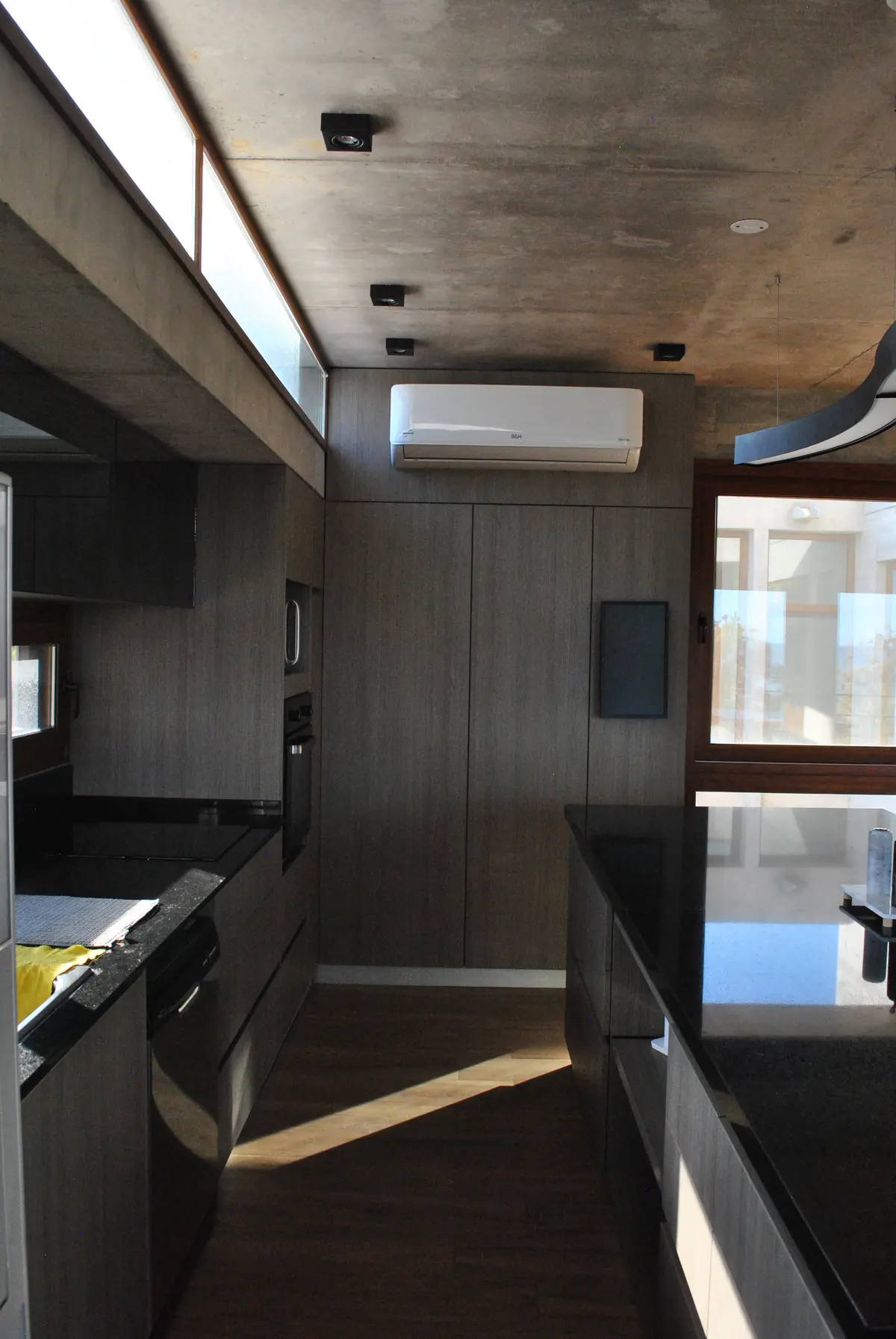 Cozinha moderna minimalista com teto de concreto e armários cinza — projeto Casa FSC, por TAVA Coop, em Pinamar