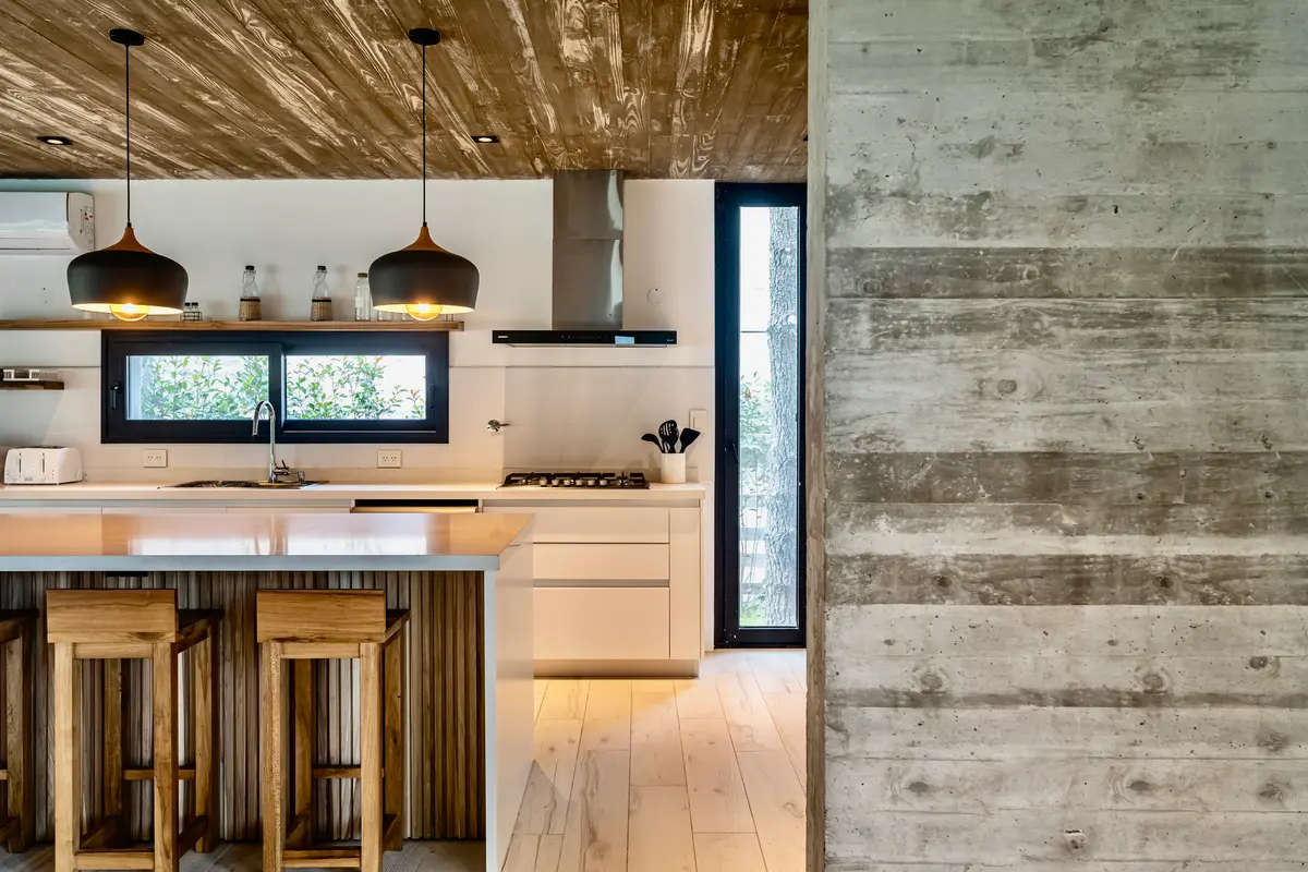 Cozinha moderna rústica com teto de madeira e paredes de concreto — projeto casa la huella, por Guerrero Arquitectos, em Pinamar
