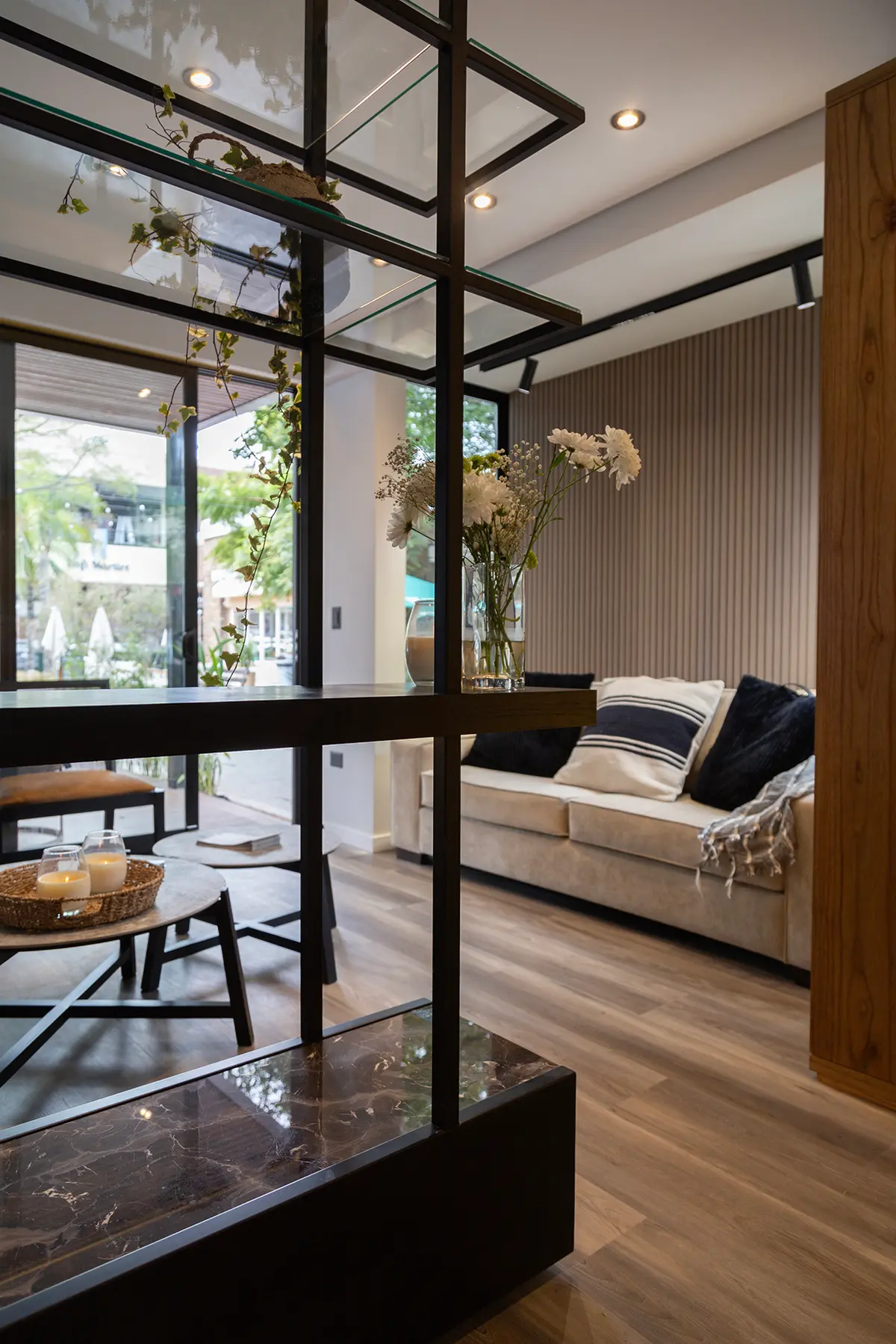 Living moderno con sofá beige, estantería de metal y pared de lamas — proyecto Interiorismo Tiny House , por LINEA NETA diseño interior , en B1648 Tigre