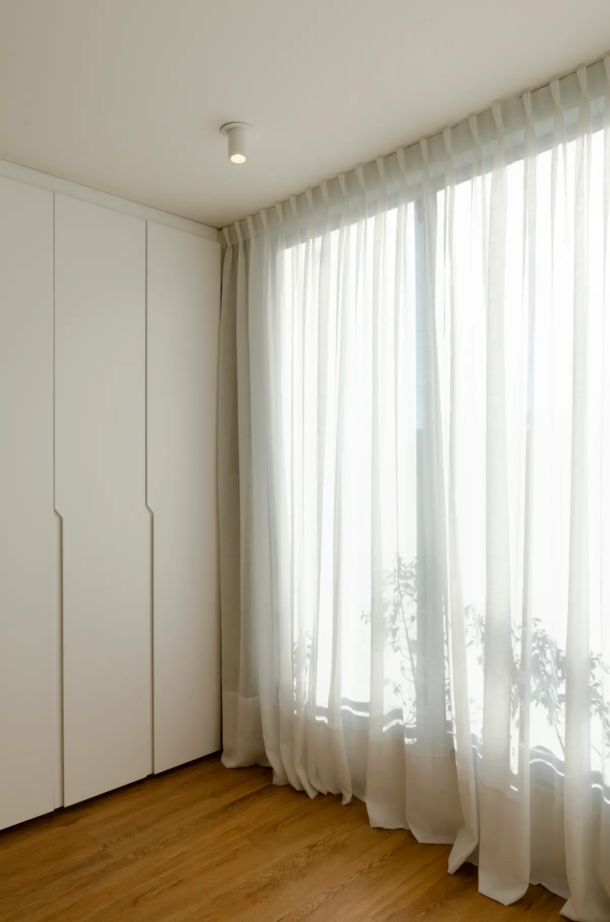 Dormitorio minimalista con ventanales y cortinas de lino, armarios empotrados blancos — proyecto Guayra - Andrea Gonzales, por ABEJA CONCEPT, en Belgrano
