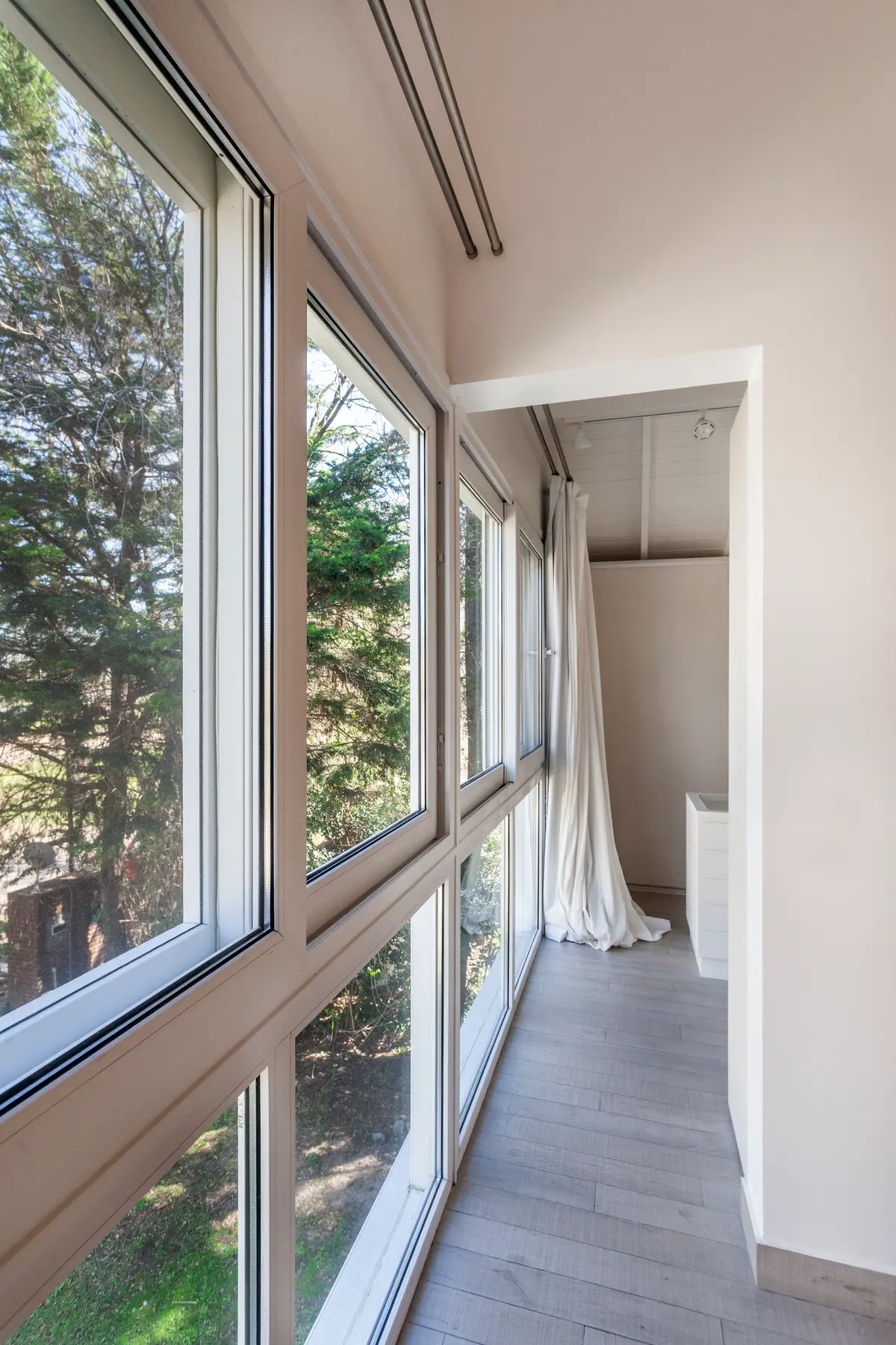 Varanda moderna com janelas do chão ao teto e vista para floresta — projeto Highland, por Lala Loviscek arquitecta, em Pilar