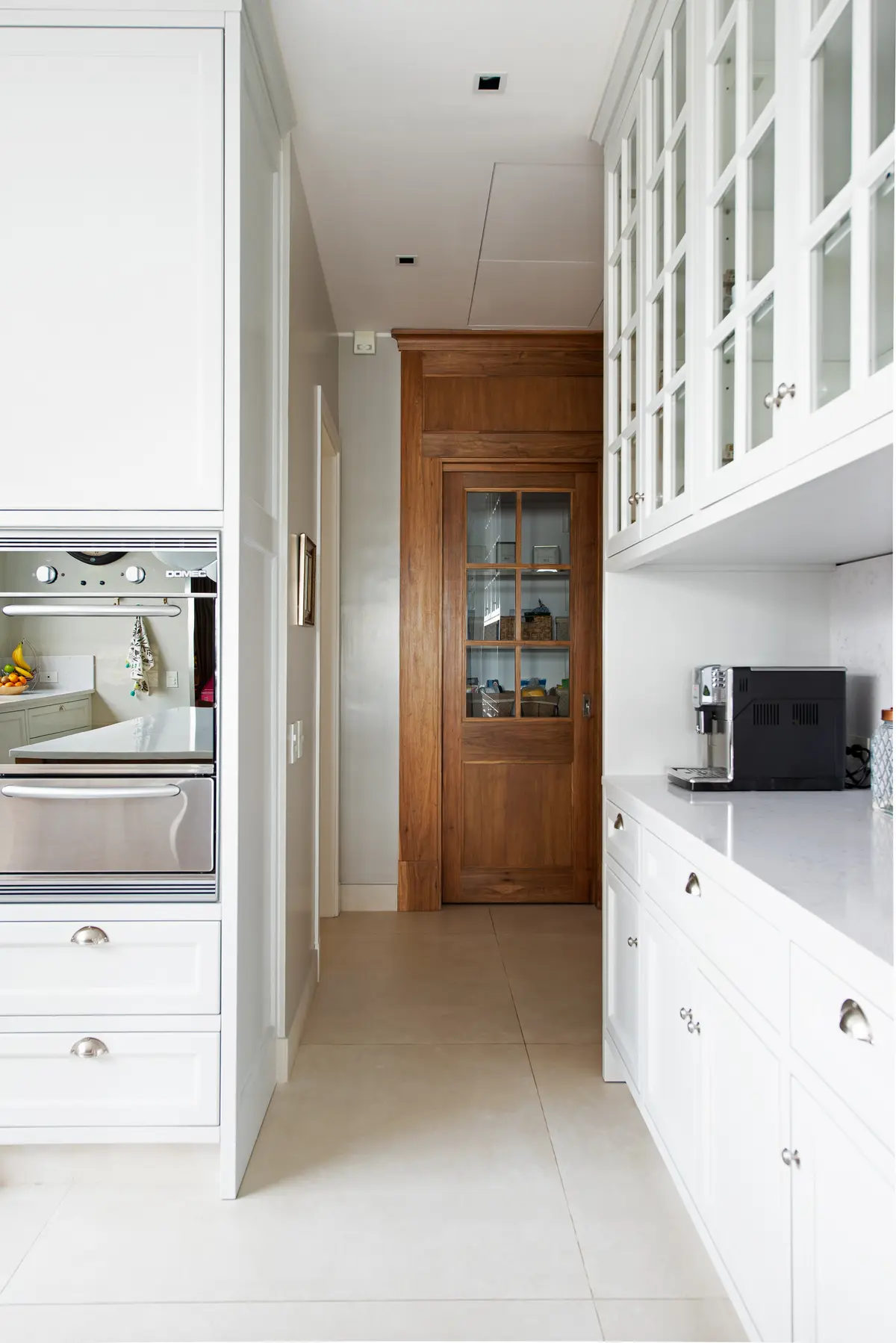 Cozinha moderna com porta de madeira e armários brancos — projeto Casa MF, por Estudio Junor, em Belén de Escobar