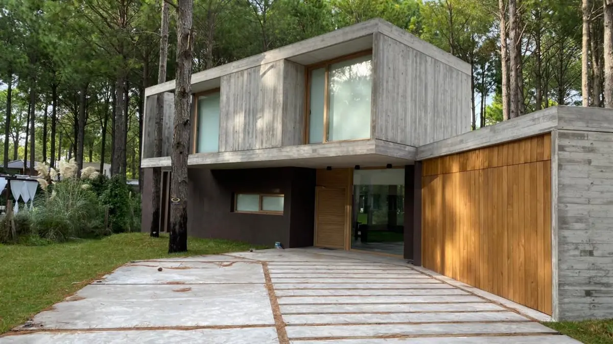 Fachada moderna de concreto e madeira em floresta — projeto Casa G, por TAVA Coop, em Pinamar