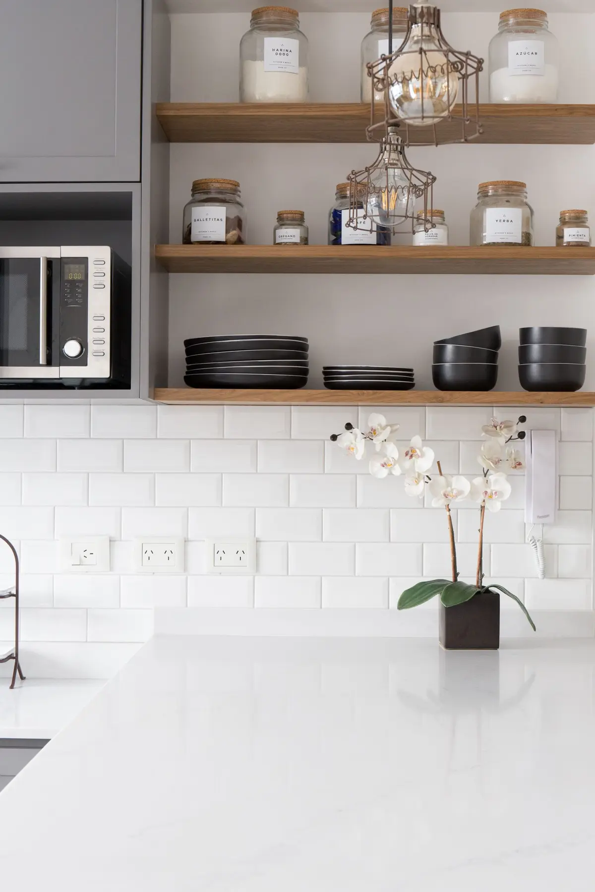 Cocina minimalista con mesadas blancas, estantes de madera y accesorios ordenados — proyecto Obra Olazábal II, por SYA Arquitectas, en Belgrano