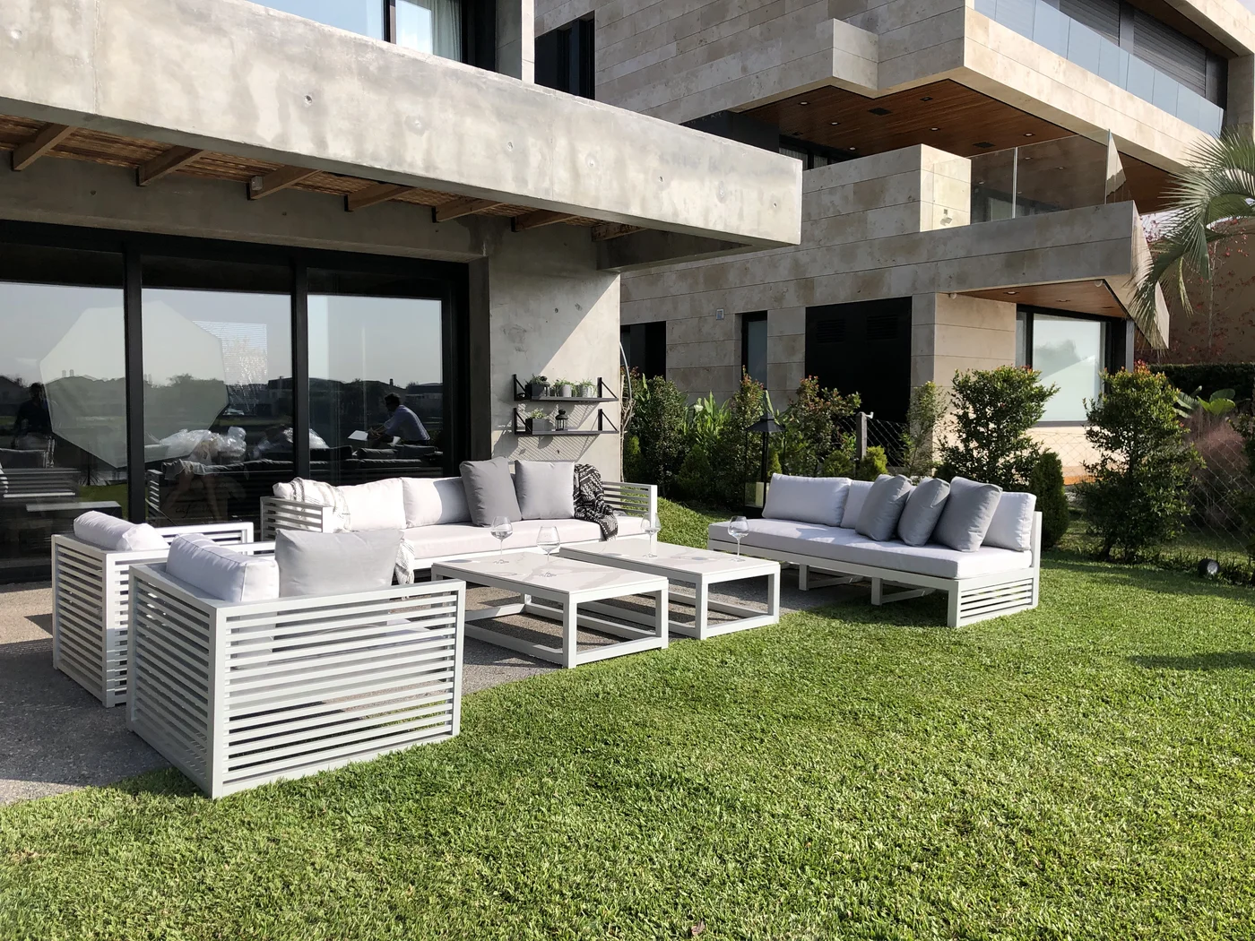 Terraza moderna con sofá modular beige y mesas de piedra.