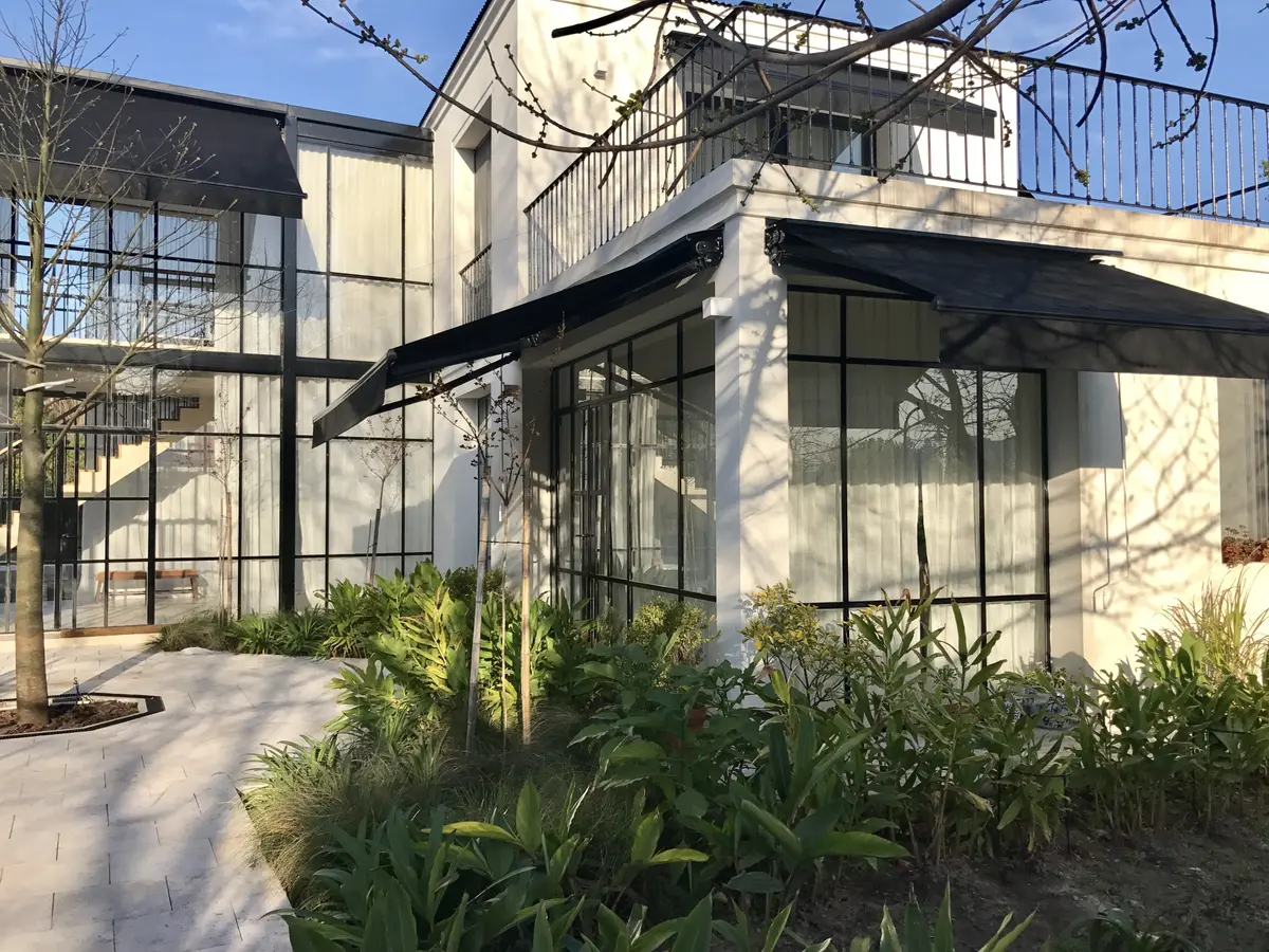fachada moderna blanca con ventanales amplios y vegetación — proyecto CASA DEL PUENTE, por Estudio Xime Fontan Balestra, en General Pacheco