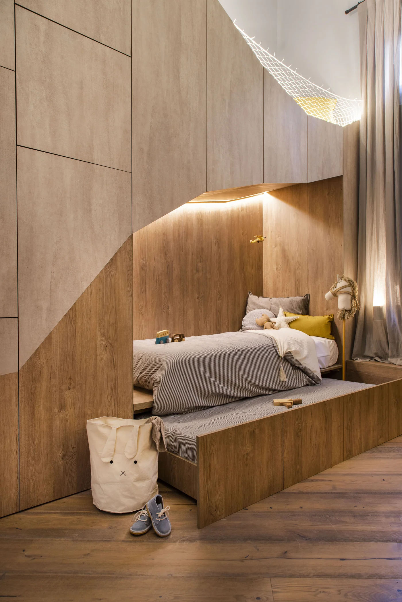 Habitación con cama nido de madera, iluminación indirecta y hamaca de red.