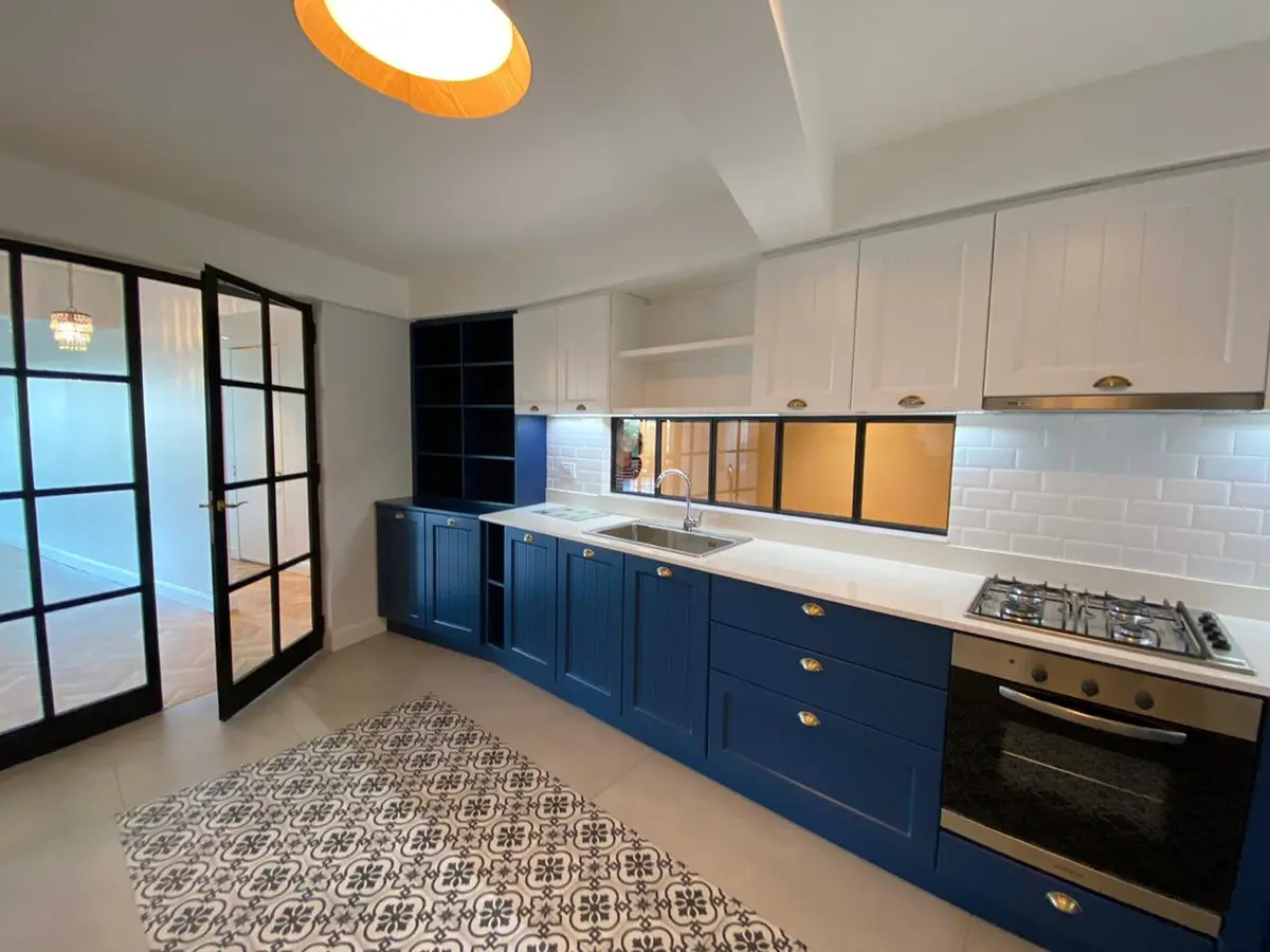 Cozinha moderna com armários azuis e brancos e detalhes industriais — projeto Casa Olleros, por Gutman+Lehrer Arquitectas, em CABA