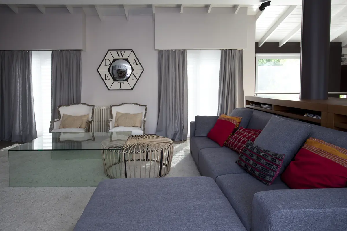 Sala moderna com painéis, sofá modular e espelho hexagonal — projeto Obra Martínez, por M. Beatriz Gonzalez Zuelgaray, em Martínez