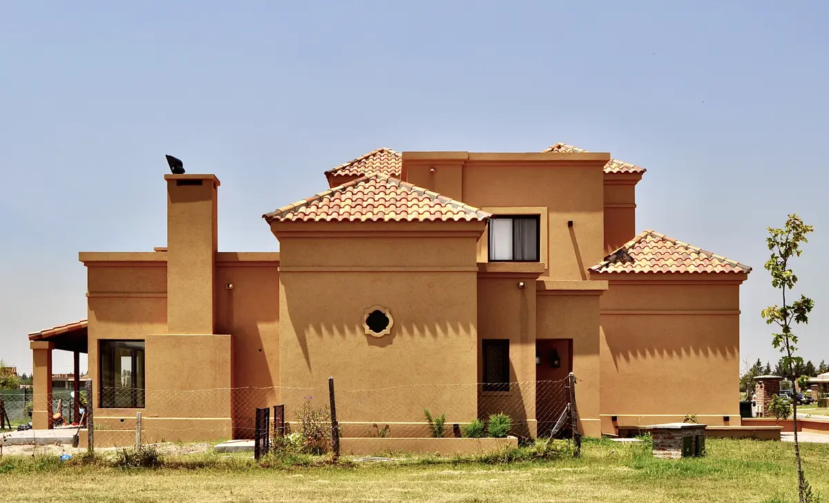 Fachada de casa estilo mediterrâneo com telhados de cerâmica terracota e chaminé — projeto San Marcos, por Marconi Silva Arquitectos, em Benavidez