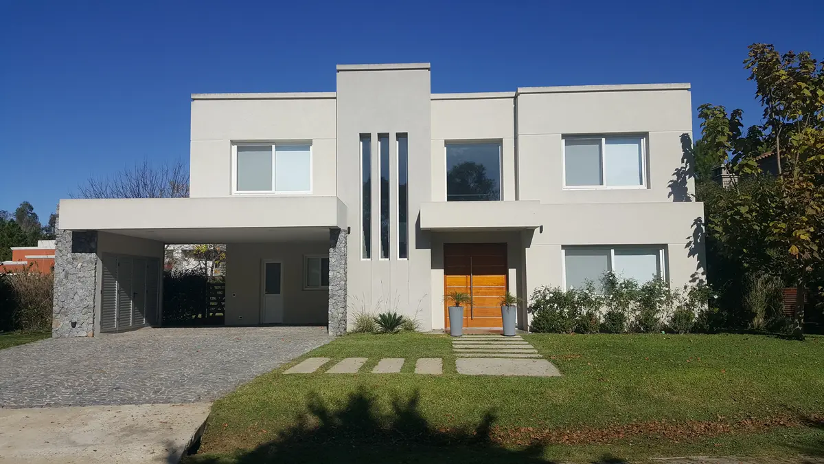 Fachada moderna de dos plantas con amplios ventanales y concreto blanco — proyecto EL CARDAL DE LOS CARDALES L45, por LESSI ARQUITECTURA, en Los Cardales