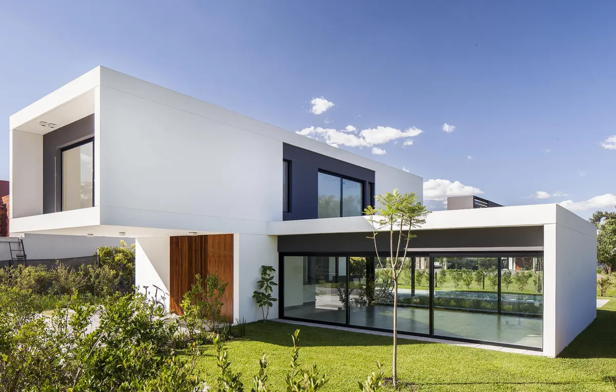 Casa moderna branca com janelas de vidro na fachada e jardim verde — projeto CASA S2, por GMARQ