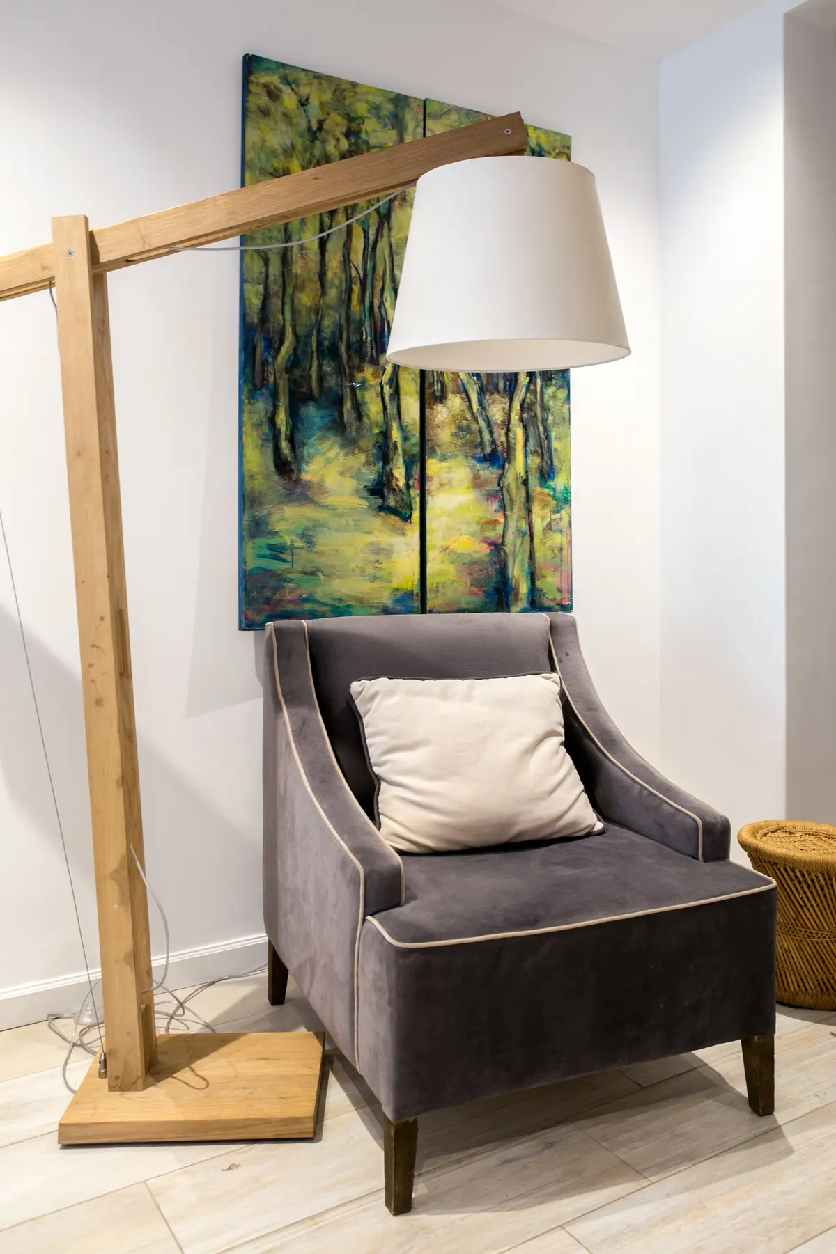 Living con sillón gris, lámpara de pie de madera y cuadro de bosque — proyecto Callao, por Mgc.arq, en CABA