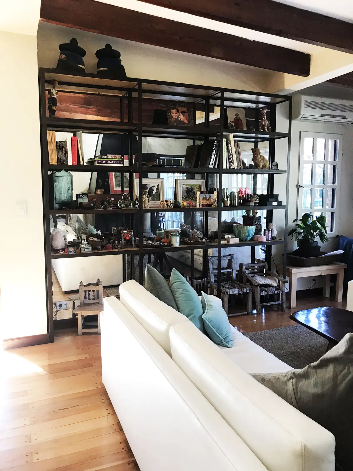 Ampla sala de estar com estante preta, sofá branco e vigas de madeira — projeto Monroe - La Horqueta, por Mgc.arq, em La Horqueta