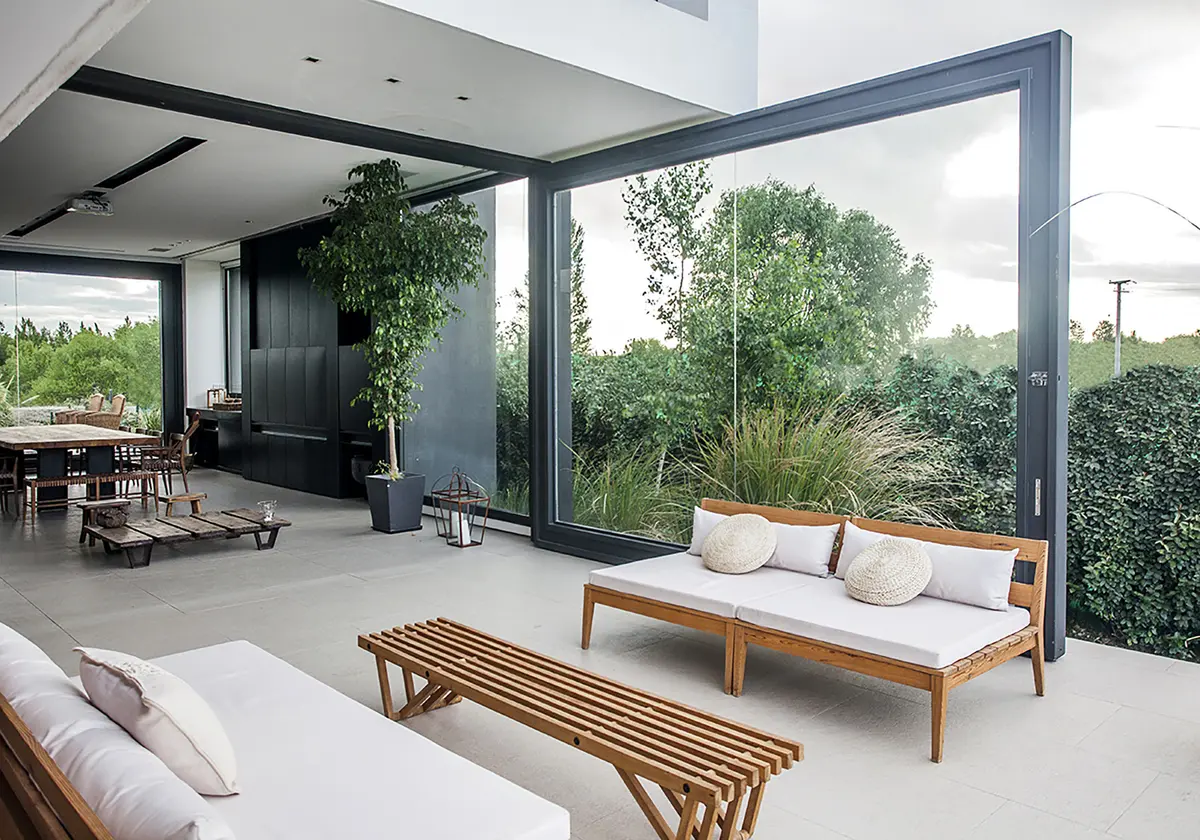 Sala moderna com amplas janelas de vidro e mobiliário externo — projeto Rampa, por Remy Arquitectos