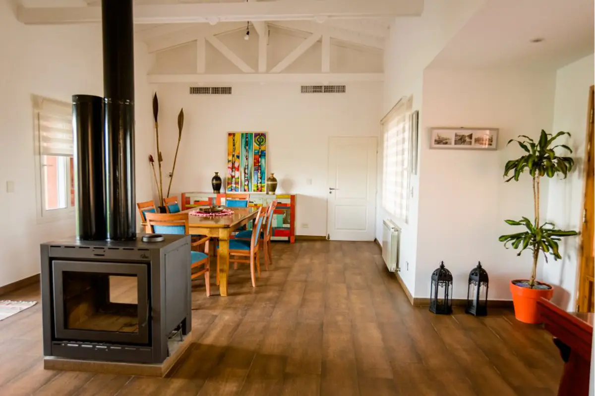 Sala de estar rústica com lareira e vigas de madeira — projeto La casa del árbol, por Estudio Fernandez Long & asoc., em Canning