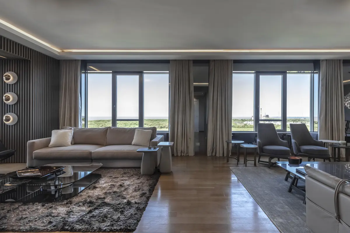 Sala de estar moderna com janelas amplas e móveis confortáveis — projeto Departamento Edificio El Faro, por Viviana Melamed, em CABA