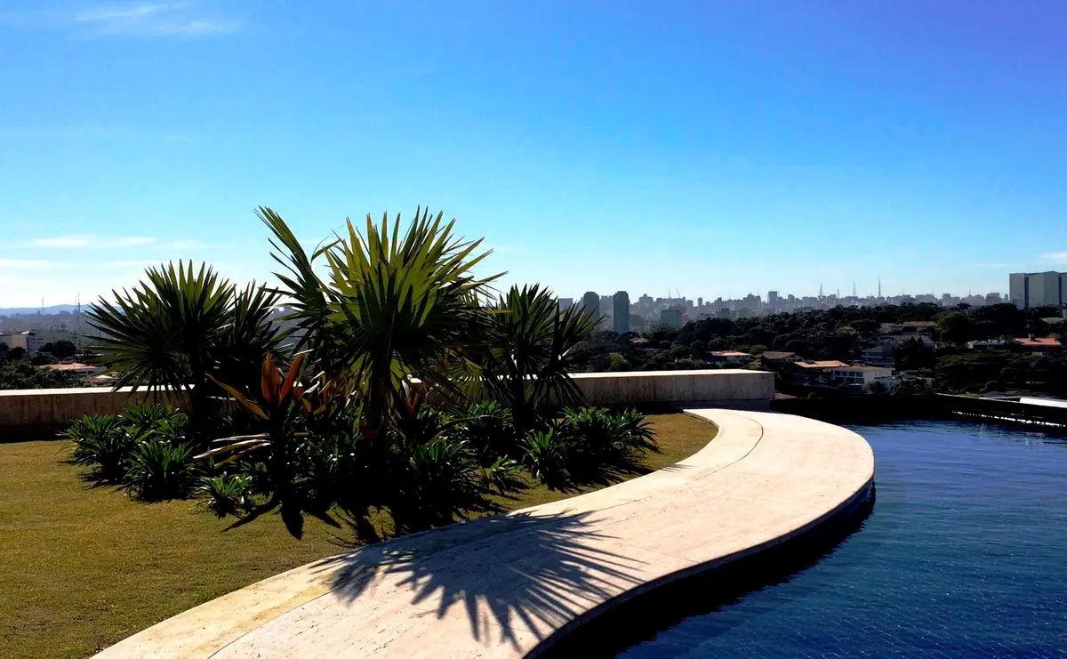 Patio con pileta, deck curvo, palmeras y vista a la ciudad — proyecto Residência HC, por Gil Fialho