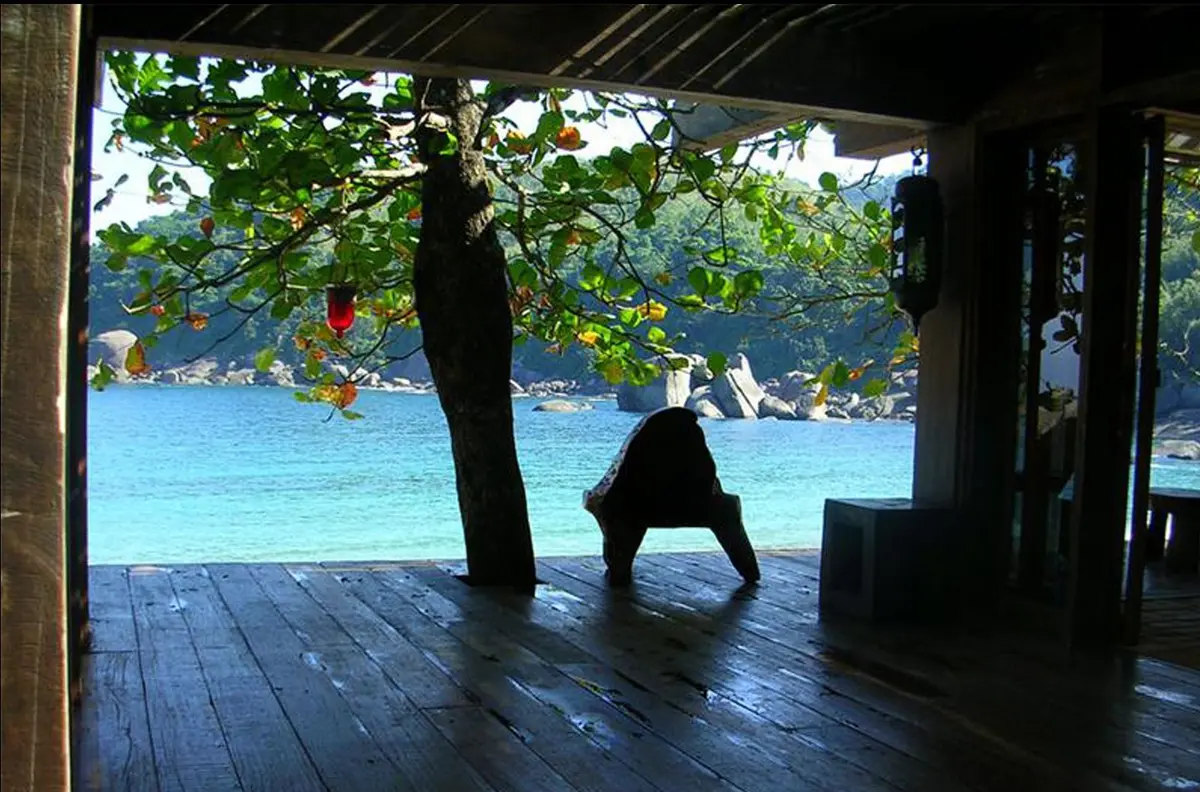 Galeria de madera con vista al lago, persona en yoga frente al agua — proyecto Fazenda Indaiauba, por Gil Fialho