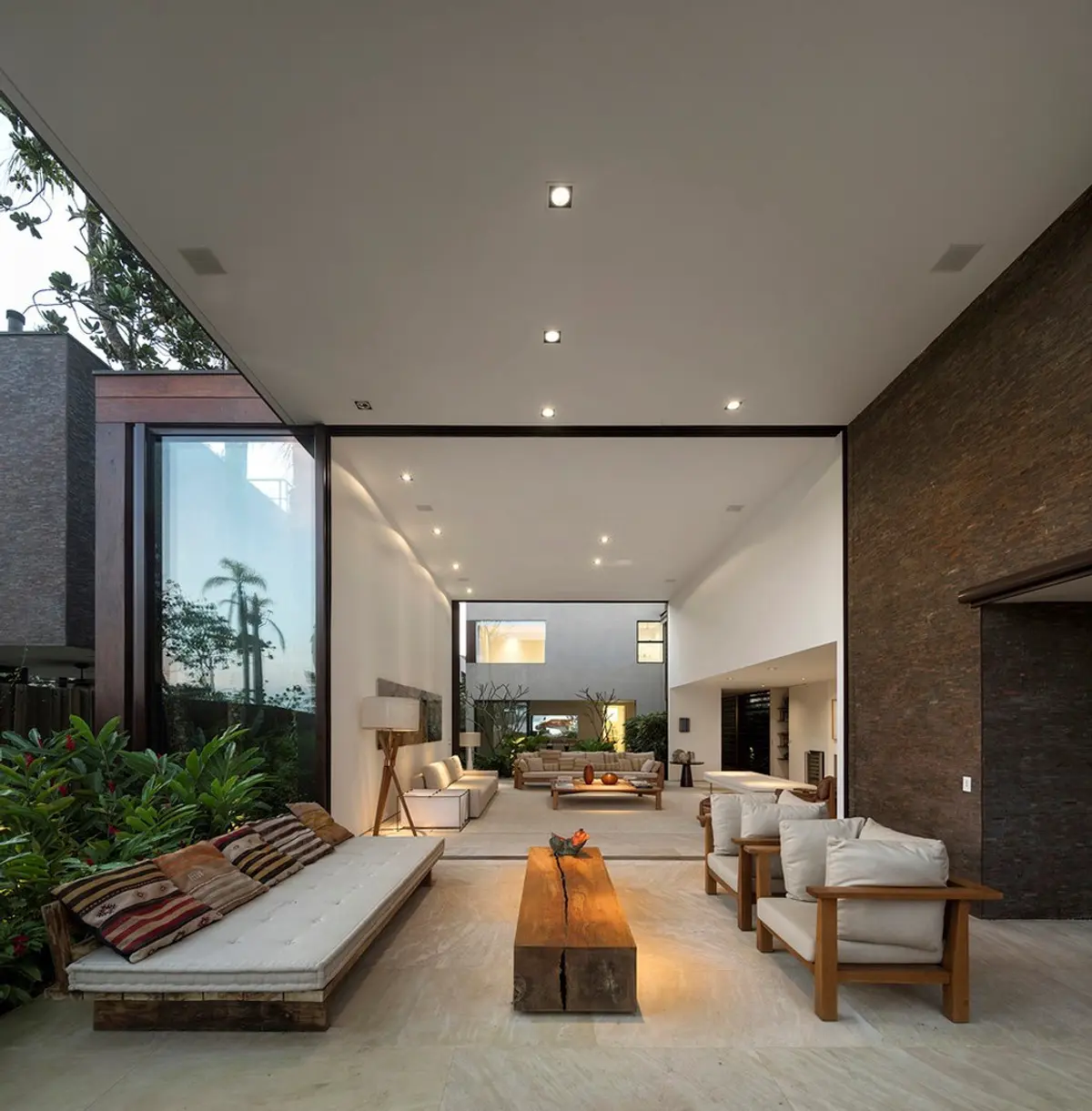 Patio interior contemporáneo con plantas, bancos y living integrado — proyecto West Whales, por Gil Fialho
