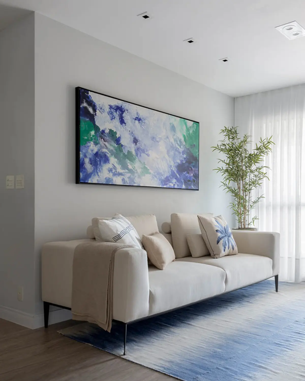 Living moderno con sofá beige, TV mural y planta junto a ventanal — proyecto Apartamento Santa Rosa, por Amanda Miranda
