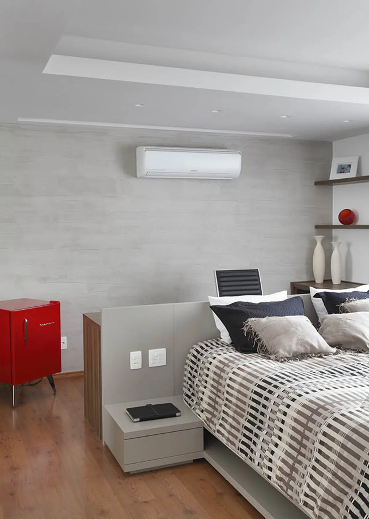 Dormitorio minimalista con aire acondicionado, cama a cuadros y frigobar rojo — proyecto Casa Barra ED, por Amanda Miranda