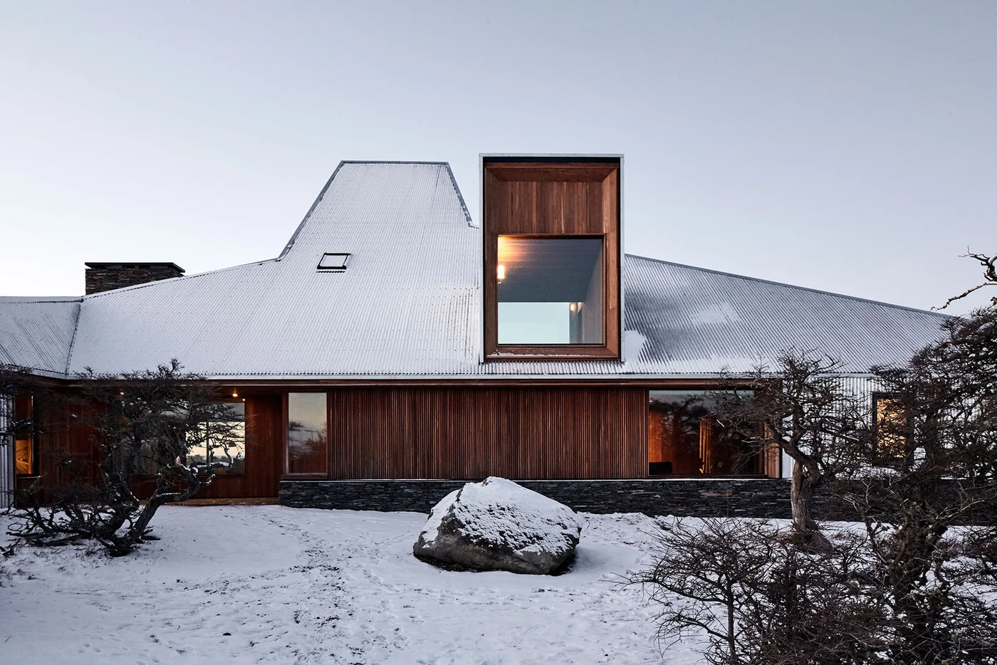 Fachada moderna de madera con extensión angular y ventana de piso a techo.