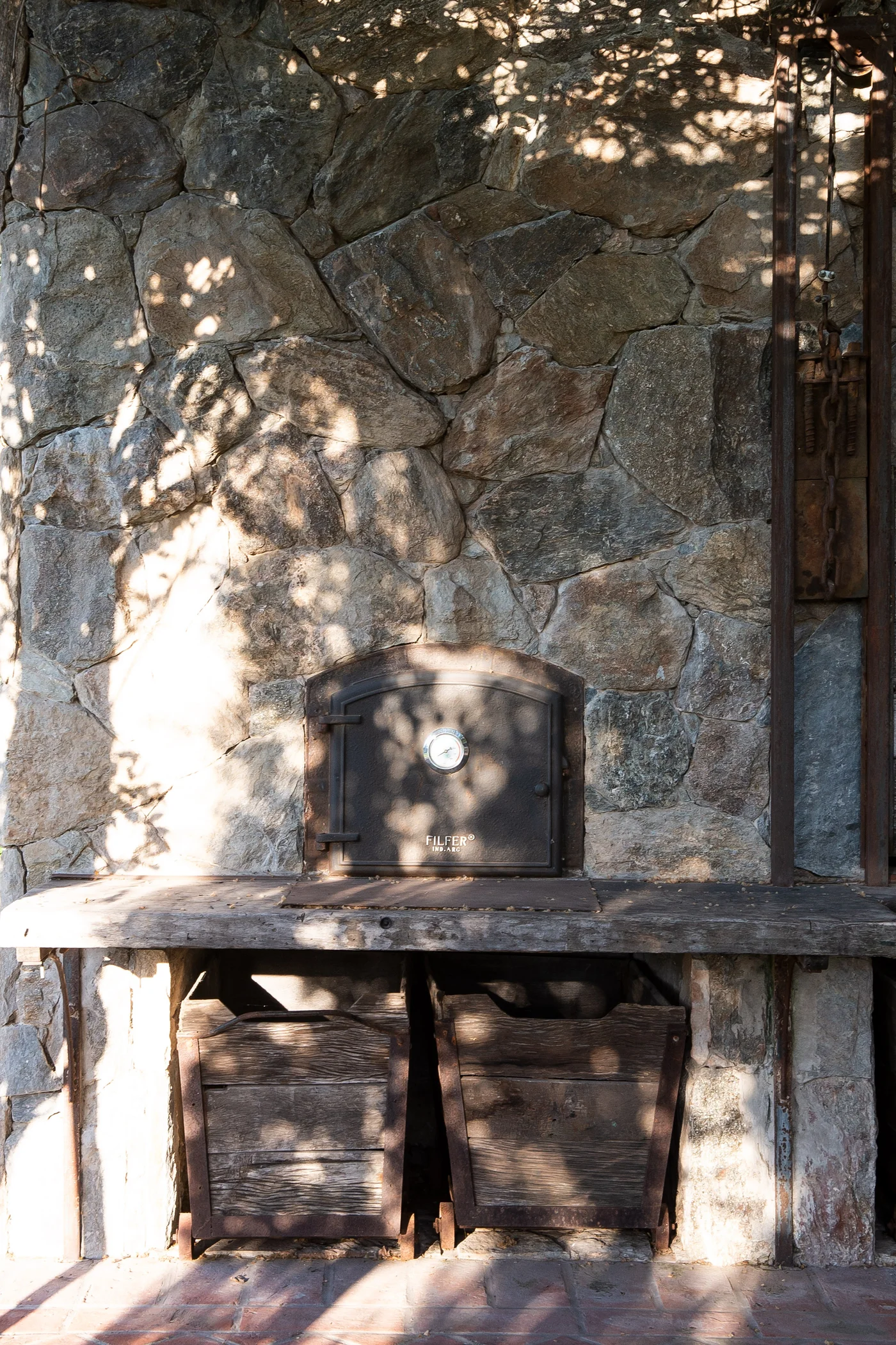 Quincho rustico con hogar de piedra y sombras de pergola
