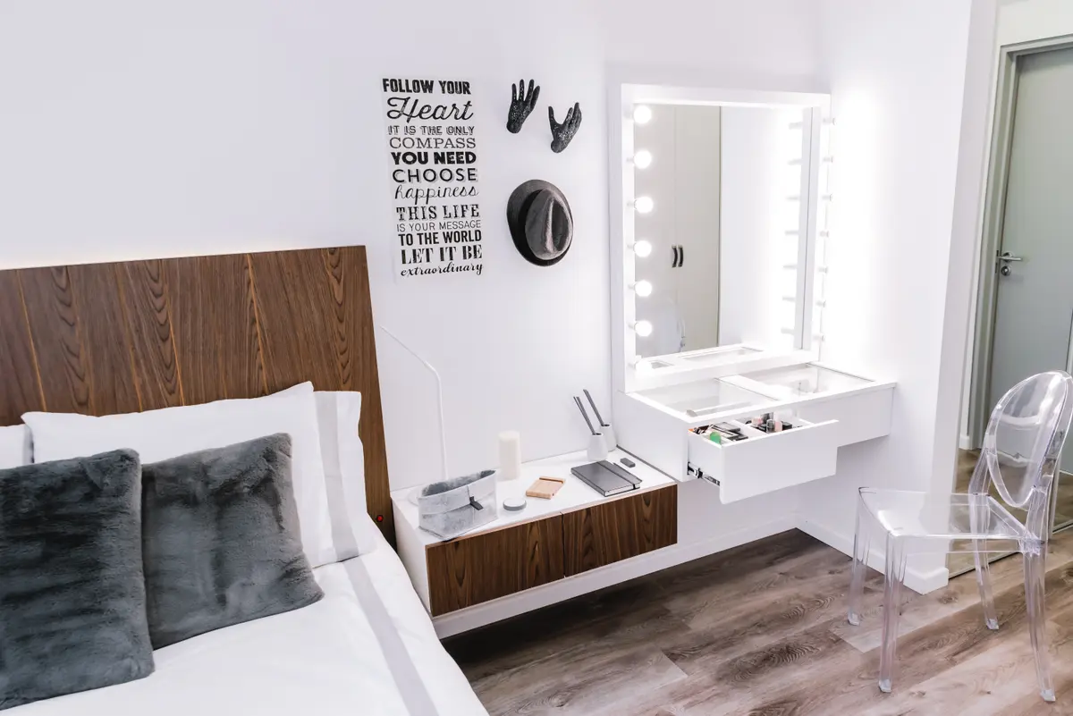 Dormitorio moderno con cama de madera, tocador iluminado y espejo grande — proyecto Cabrera, por Tali Estudio, en Palermo