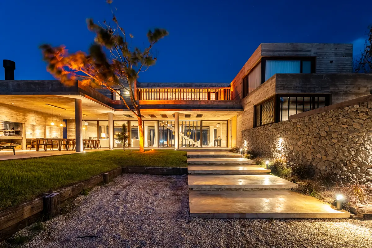 fachada moderna brutalista com iluminação quente à noite — projeto CASA sobre el MAR, por Guerrero Arquitectos, em Pinamar