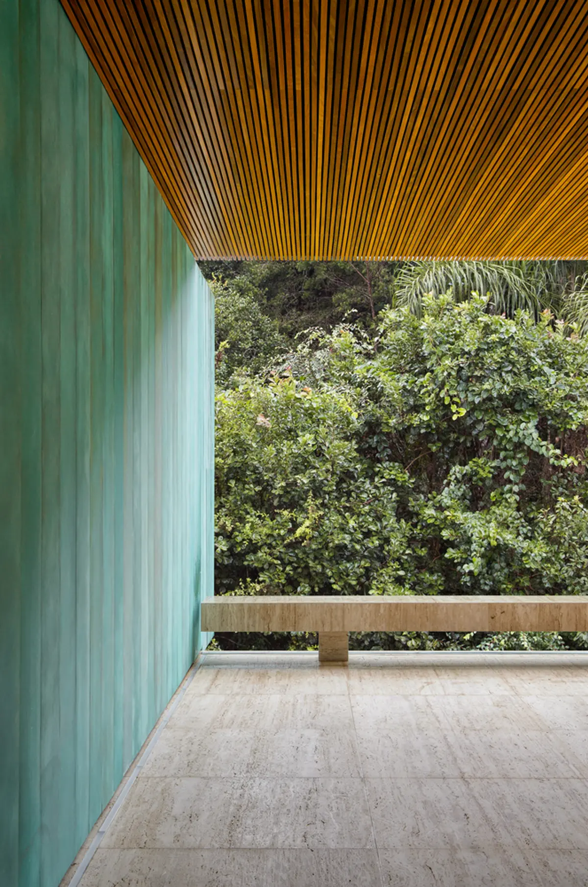 Balcón moderno con pared verde, techo de madera y vista al bosque — proyecto Casa Asa, por Studio Guilherme Torres