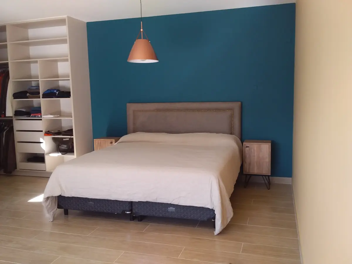 Dormitorio moderno con pared azul teal y armario blanco — proyecto Siete soles, por Design & Living, en Córdoba