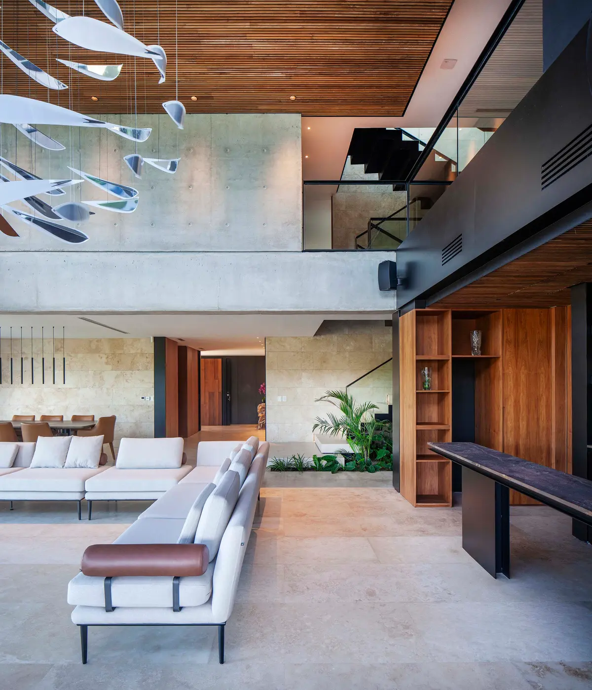 Sala de estar moderna de doble altura com iluminação escultural e detalhes em madeira — projeto Water House, por Remy Arquitectos, em Rincón de Milberg