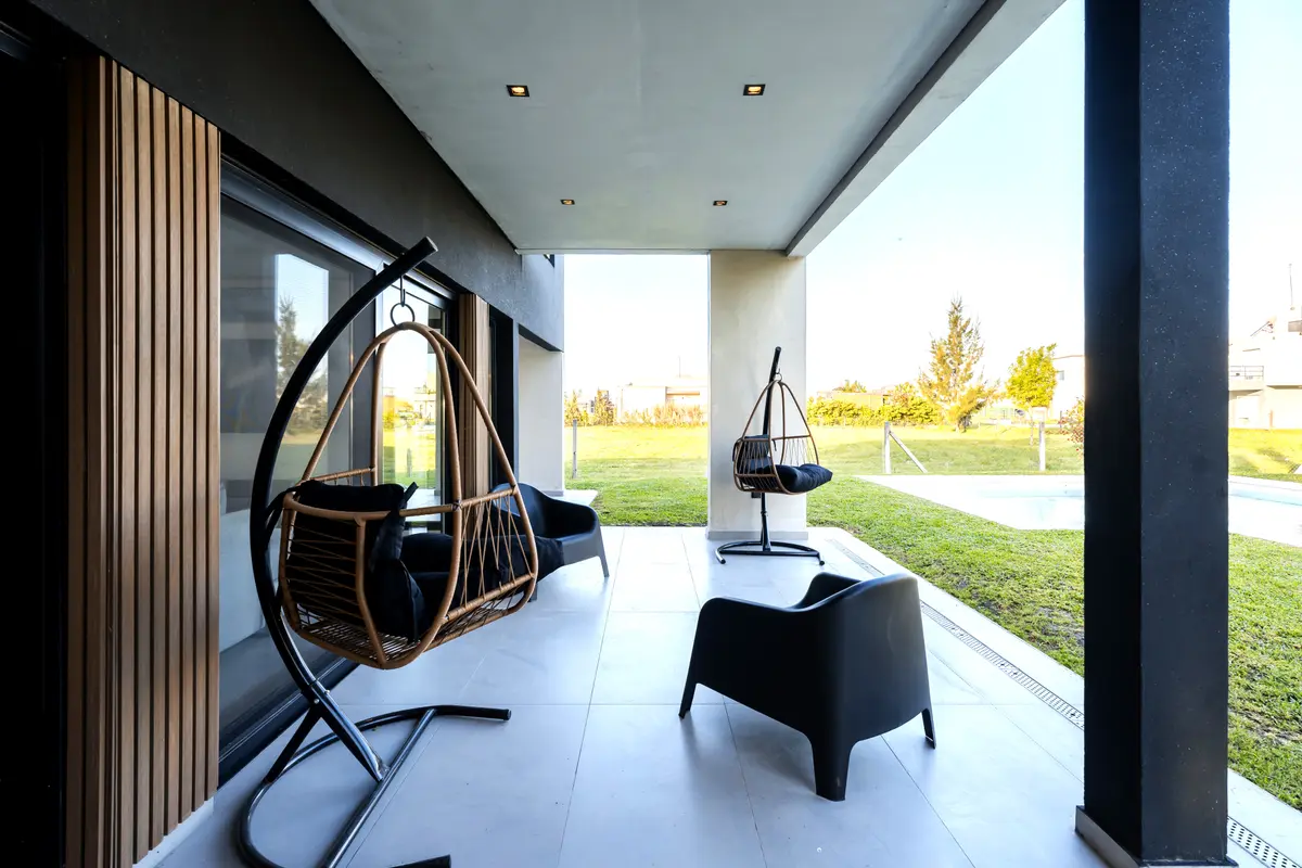 Terraza moderna con sillas colgantes de ratán y detalles en madera — proyecto Casa ALM57, por EZ architects, en Canning
