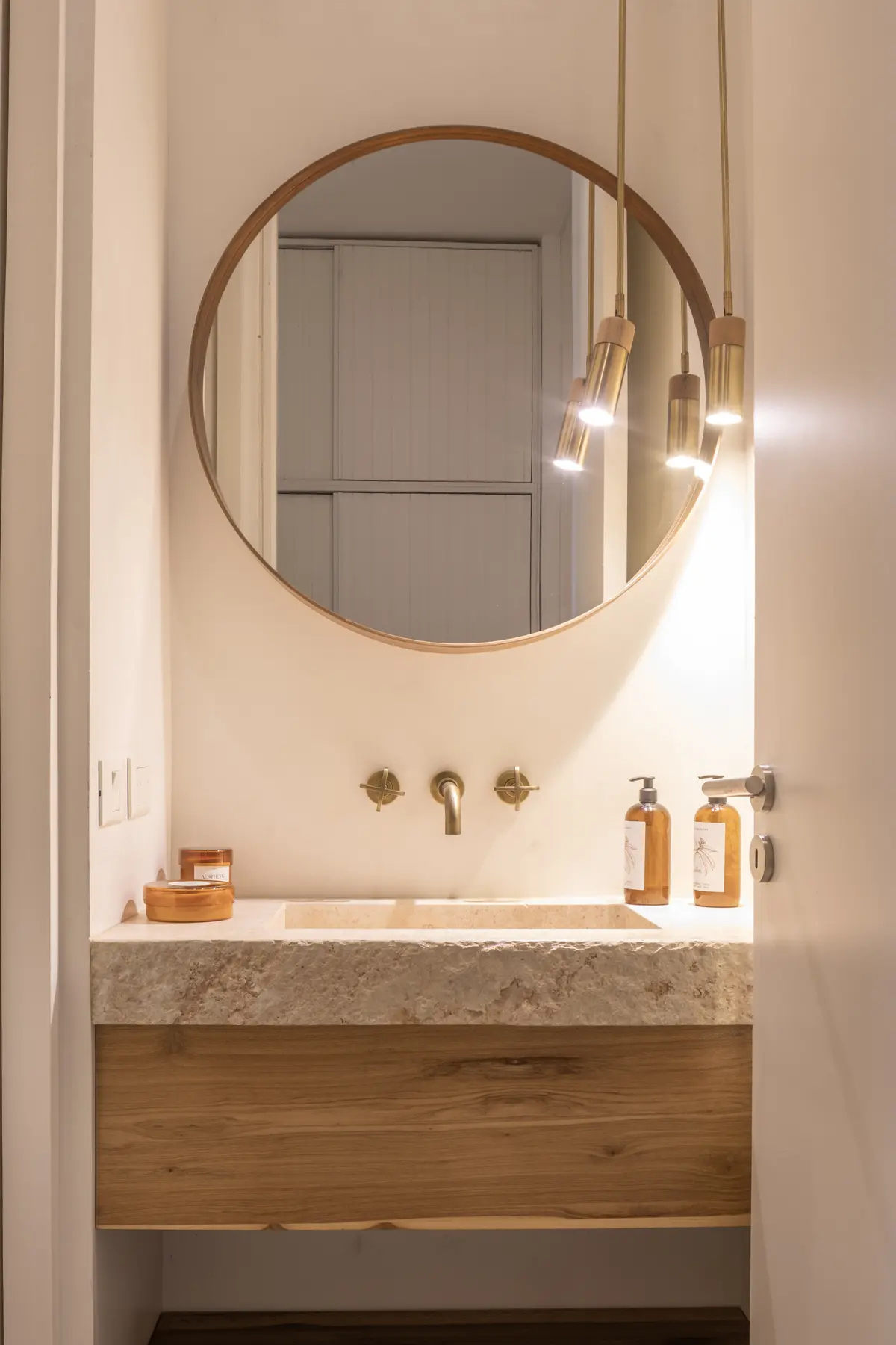 Baño moderno con espejo redondo, vanitory de madera y grifería de bronce — proyecto CASA OrAz, por Alfredo Orfila arquitectura, en San Isidro