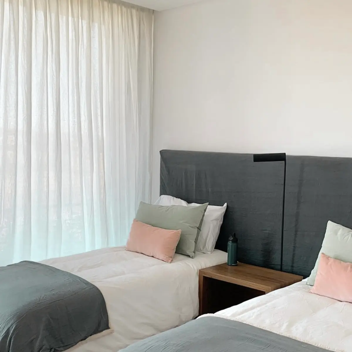 Dormitorio con dos camas, cortinas blancas y paredes grises — proyecto Estancias , por Claraboia , en Pilar