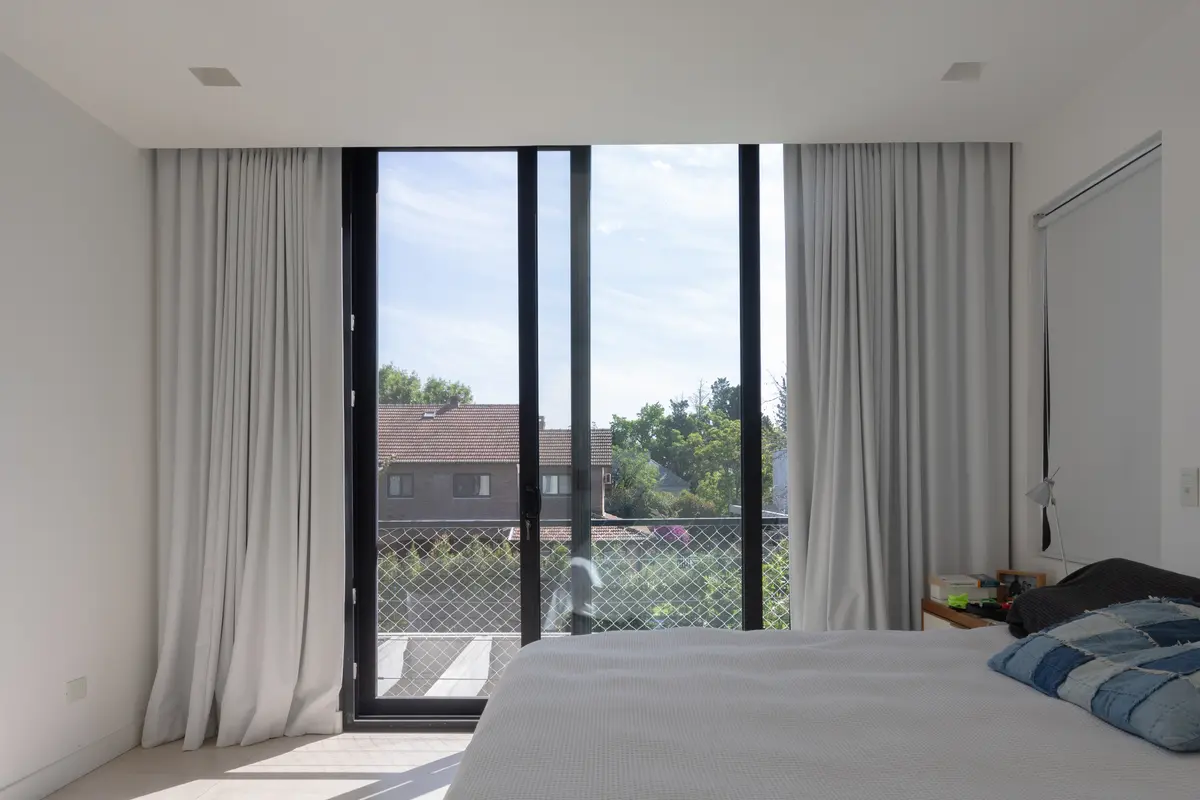 dormitorio moderno con grandes ventanales y cortinas blancas — proyecto CASA RuZa, por Alfredo Orfila arquitectura, en Benavidez