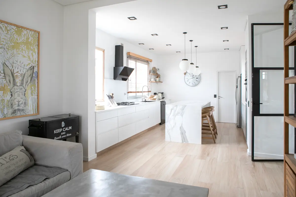 Cozinha moderna e clara com ilha, piso de madeira e arte — projeto Obra El Encuentro, por Arq. Lourdes Yarade Saravia, em Benavidez