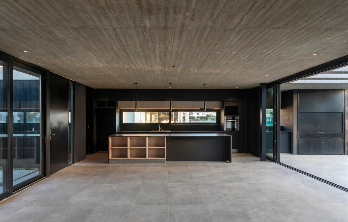 Cocina moderna minimalista con isla y techo de hormigón visto — proyecto Casa ROMA, por V2 Arquitectos, en City Bell