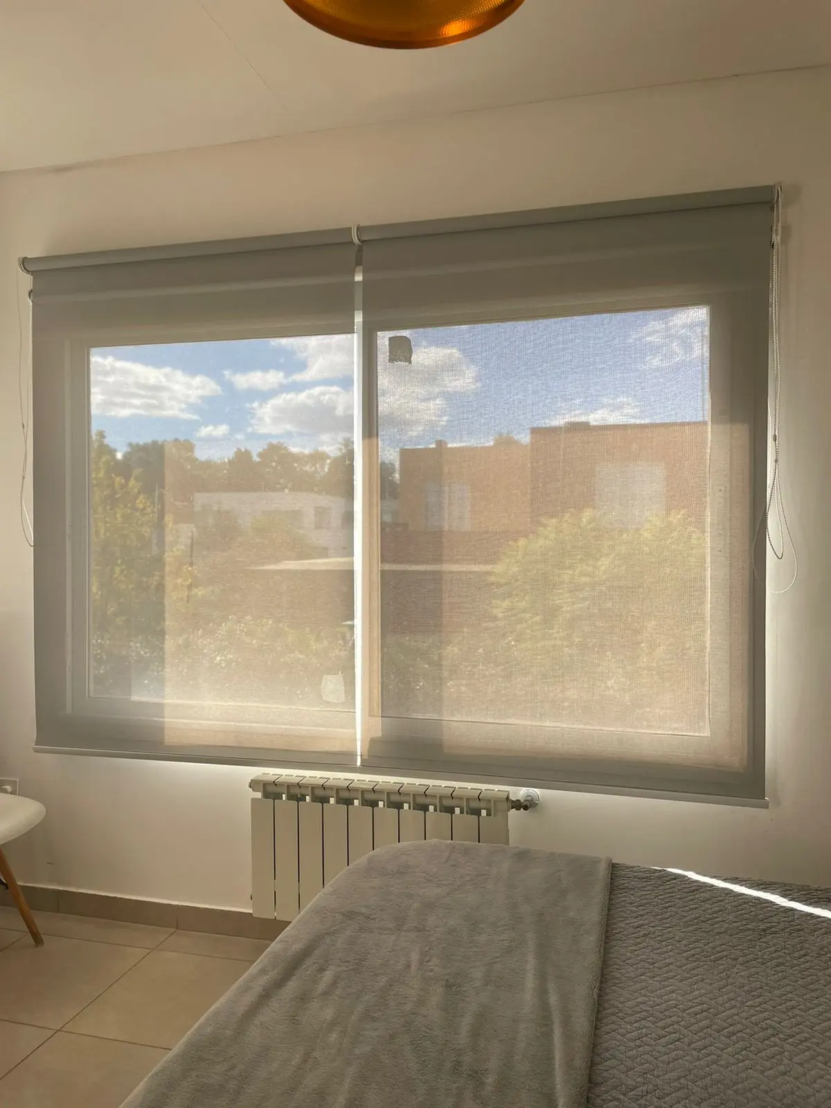 Dormitorio moderno con persianas translúcidas y cama grande — proyecto ROLLER SUNSCREEN 5% PREMIUM COLOR GRIS/GRIS, por Cortinas Oeste Roller, en Pilar