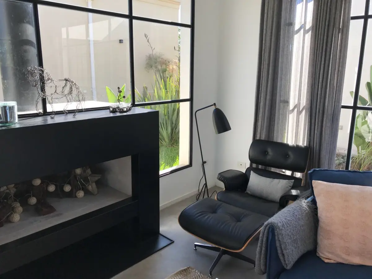 Sala de estar moderna com lareira preta e janelas grandes — projeto Casa Las Liebres, por Mazzinghi Sanchez, em Garin