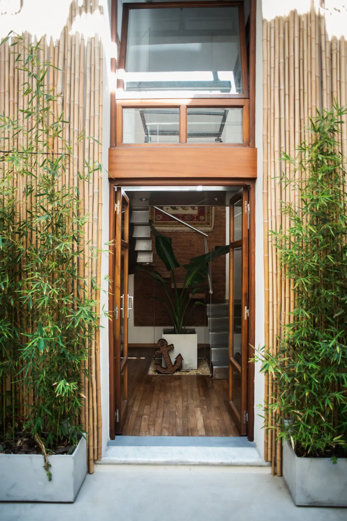 Entrada com bambu, porta dupla e escada flutuante — projeto Defensa, por Estudio Basa, em CABA