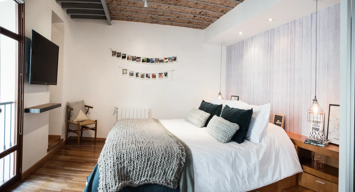 Dormitorio industrial con vigas de madera expuestas y luz cálida — proyecto Defensa, por Estudio Basa, en CABA