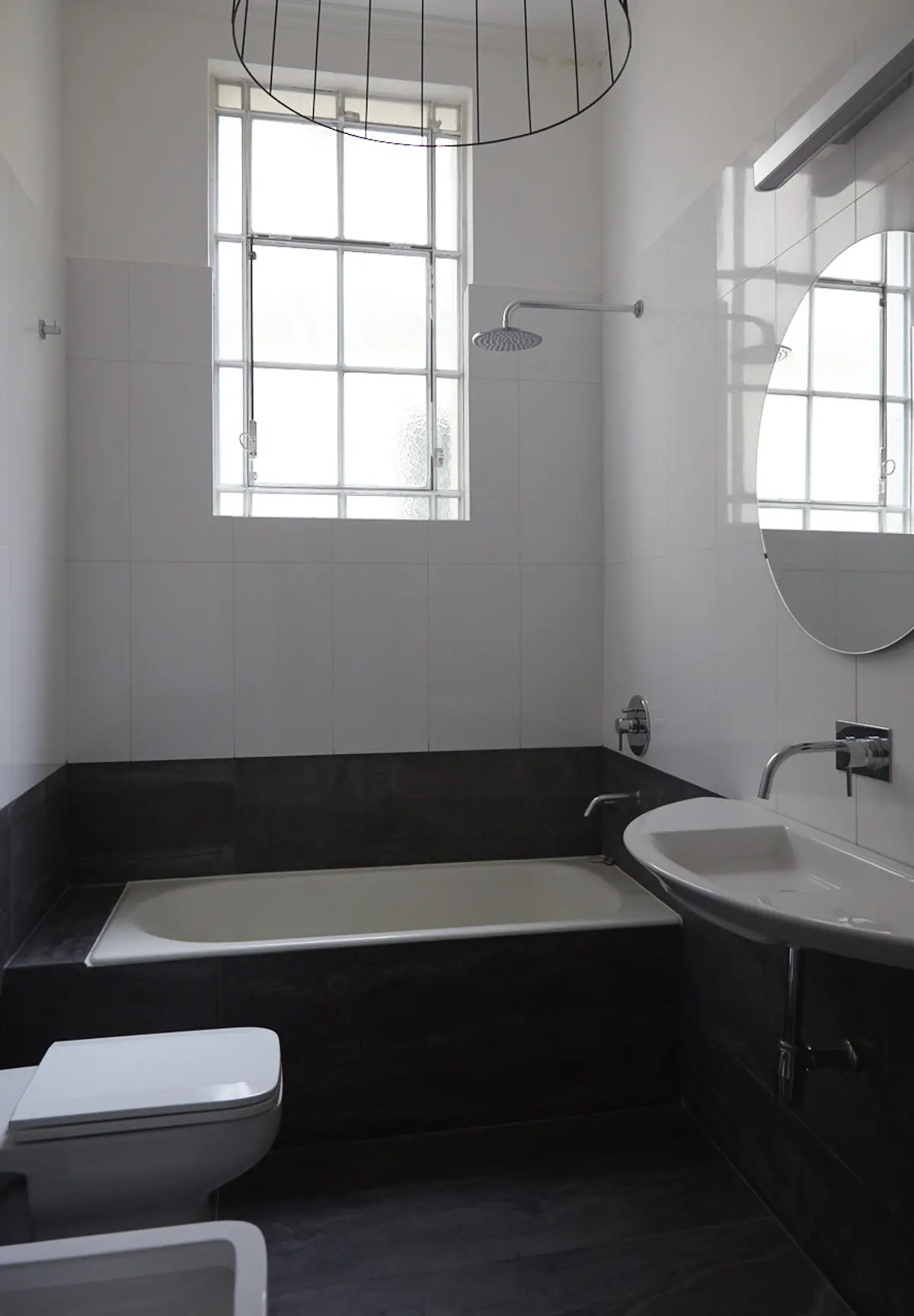 Baño moderno con ventana grande, bañera exenta y lavabo ovalado — proyecto BERUTI 2, por Estudio Trama, en Palermo