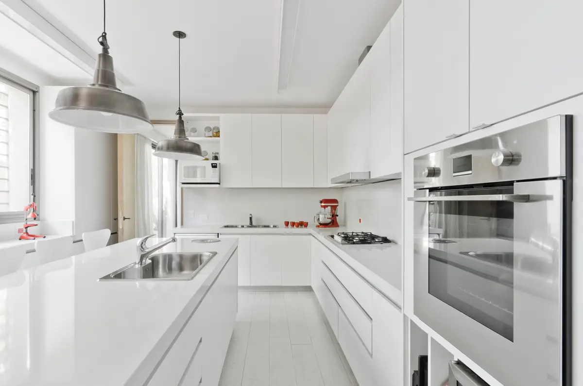 Cocina moderna minimalista blanca con isla grande y luz natural — proyecto Casa P, por Estudio Dado, en San Isidro