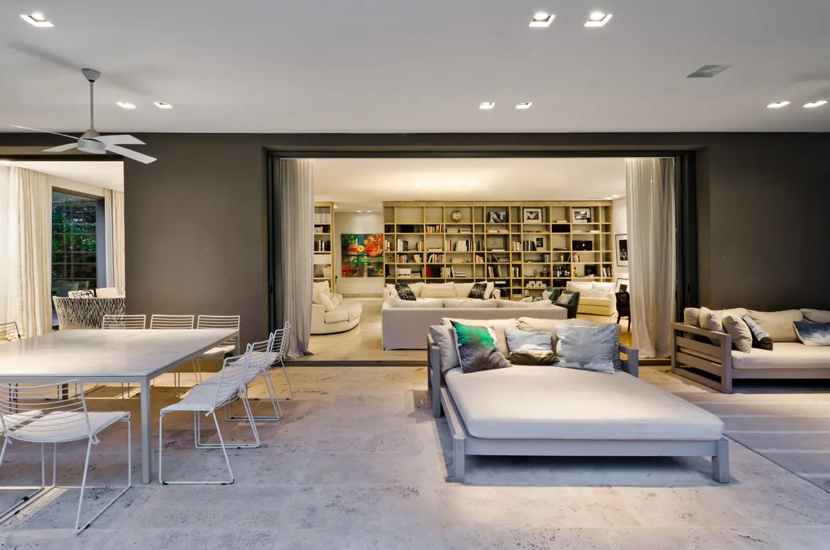 Sala de estar e jantar moderna integrada com pátio e estantes embutidas — projeto Casa H, por Estudio Dado, em Belgrano