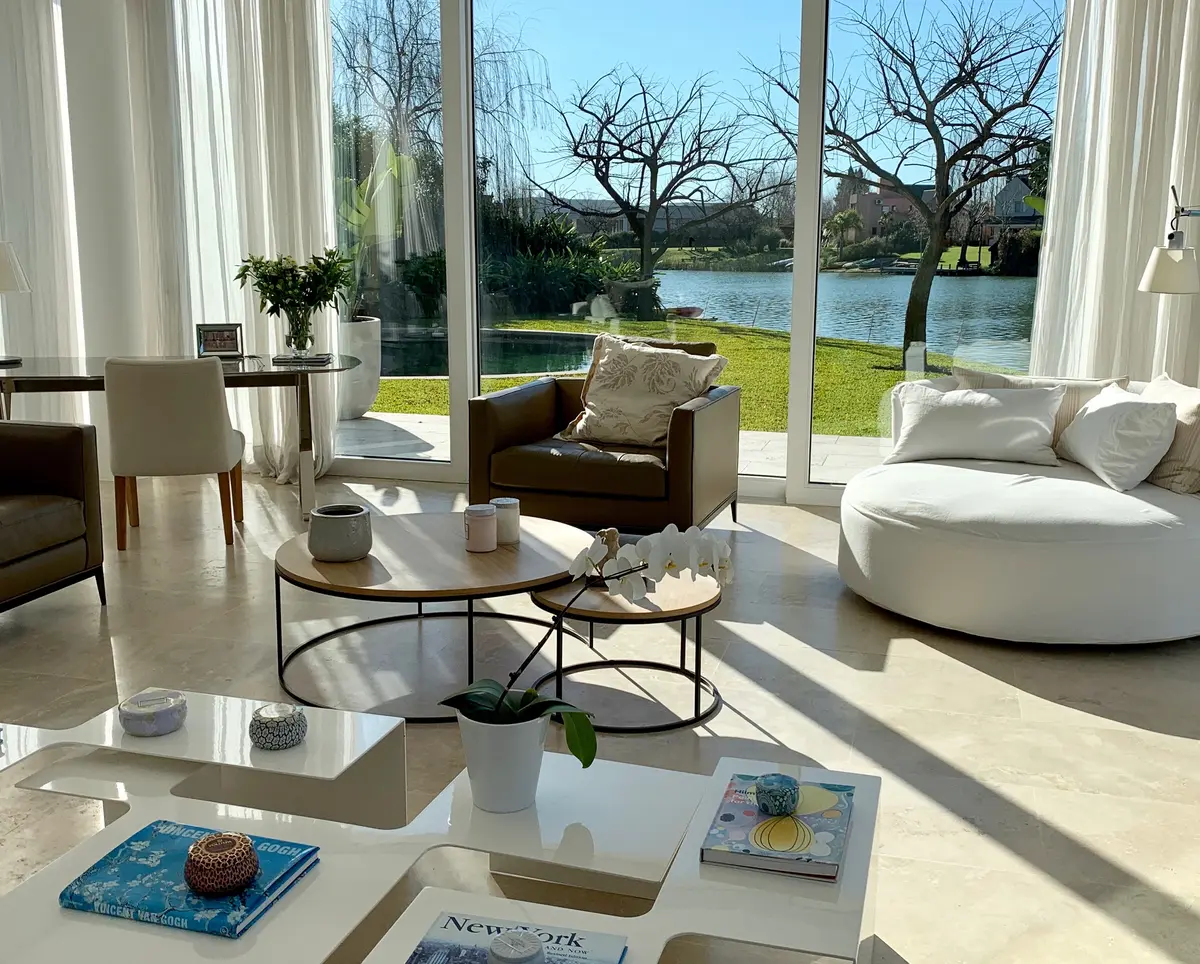 Sala de estar moderna com vista para jardim e janelas do chão ao teto — projeto CASA LAGUNA, por Estudio Xime Fontan Balestra, em Tigre