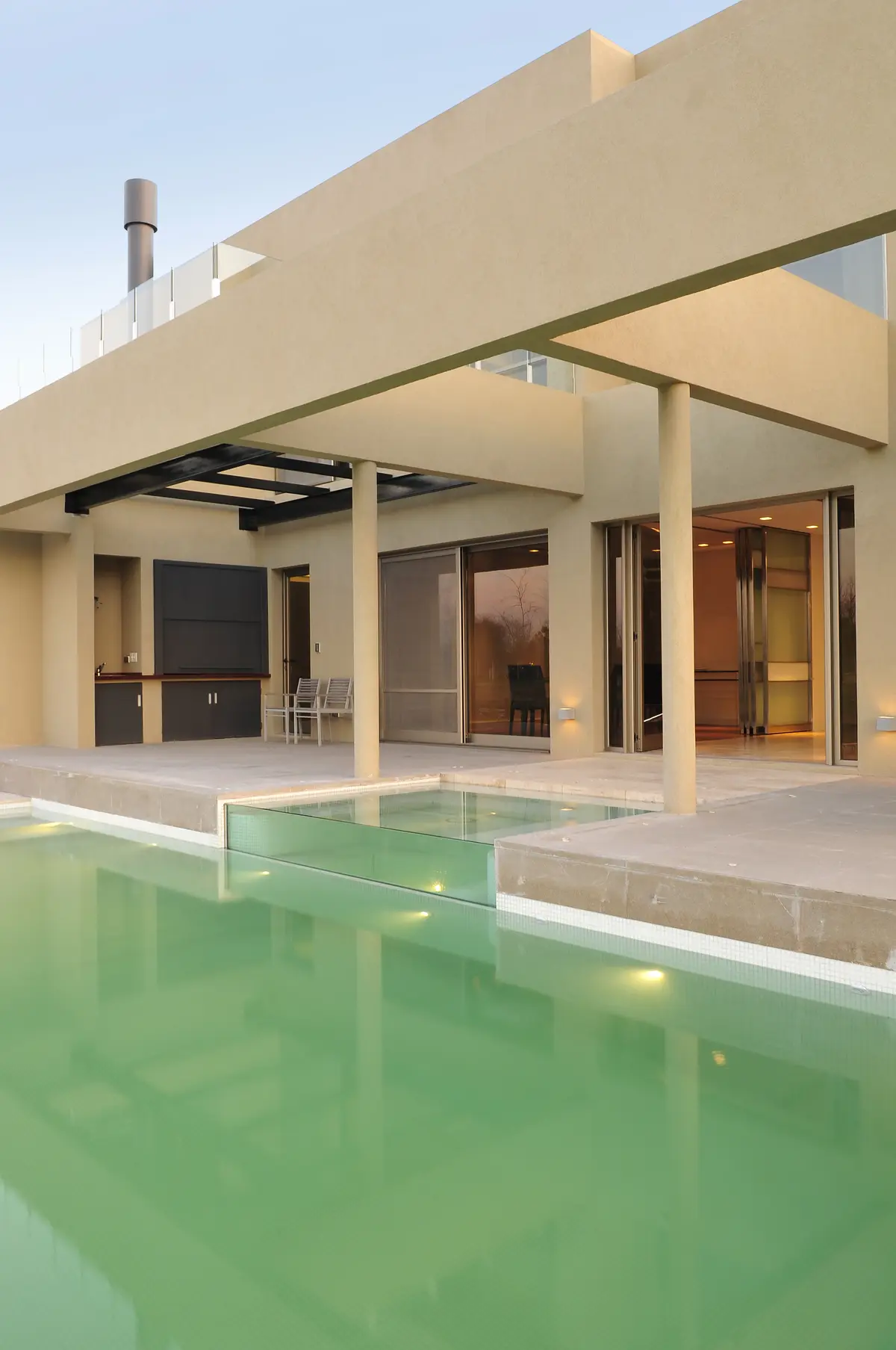 Piscina moderna con pared de vidrio y deck de piedra — proyecto Moderna Seducción, por Apaarquitectura, en Tigre