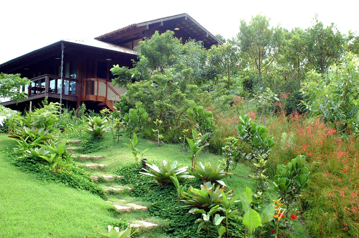 Casa moderna con jardín exuberante y sendero de piedra entre plantas — proyecto Fazenda Indaiauba, por Gil Fialho