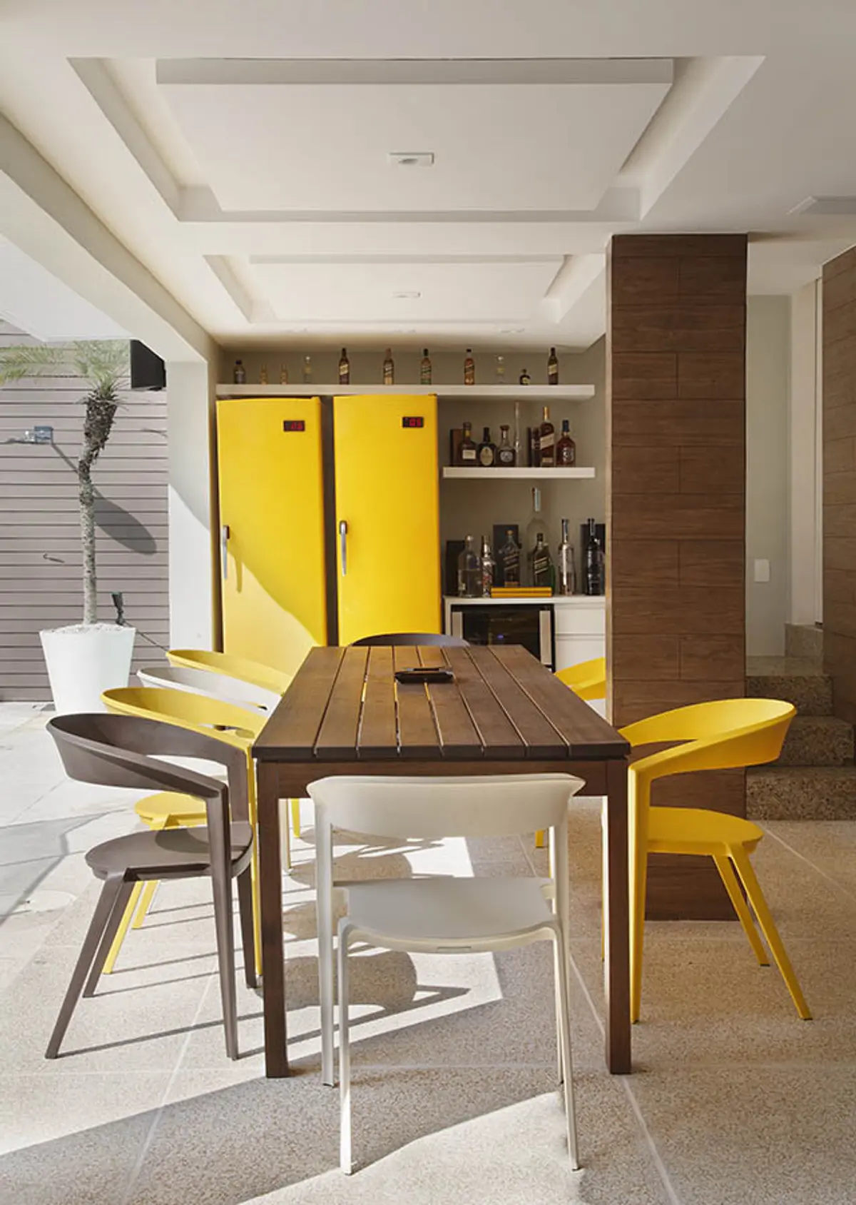 Comedor moderno con mesa madera, sillas amarillas y muebles empotrados — proyecto Casa Barra ED, por Amanda Miranda